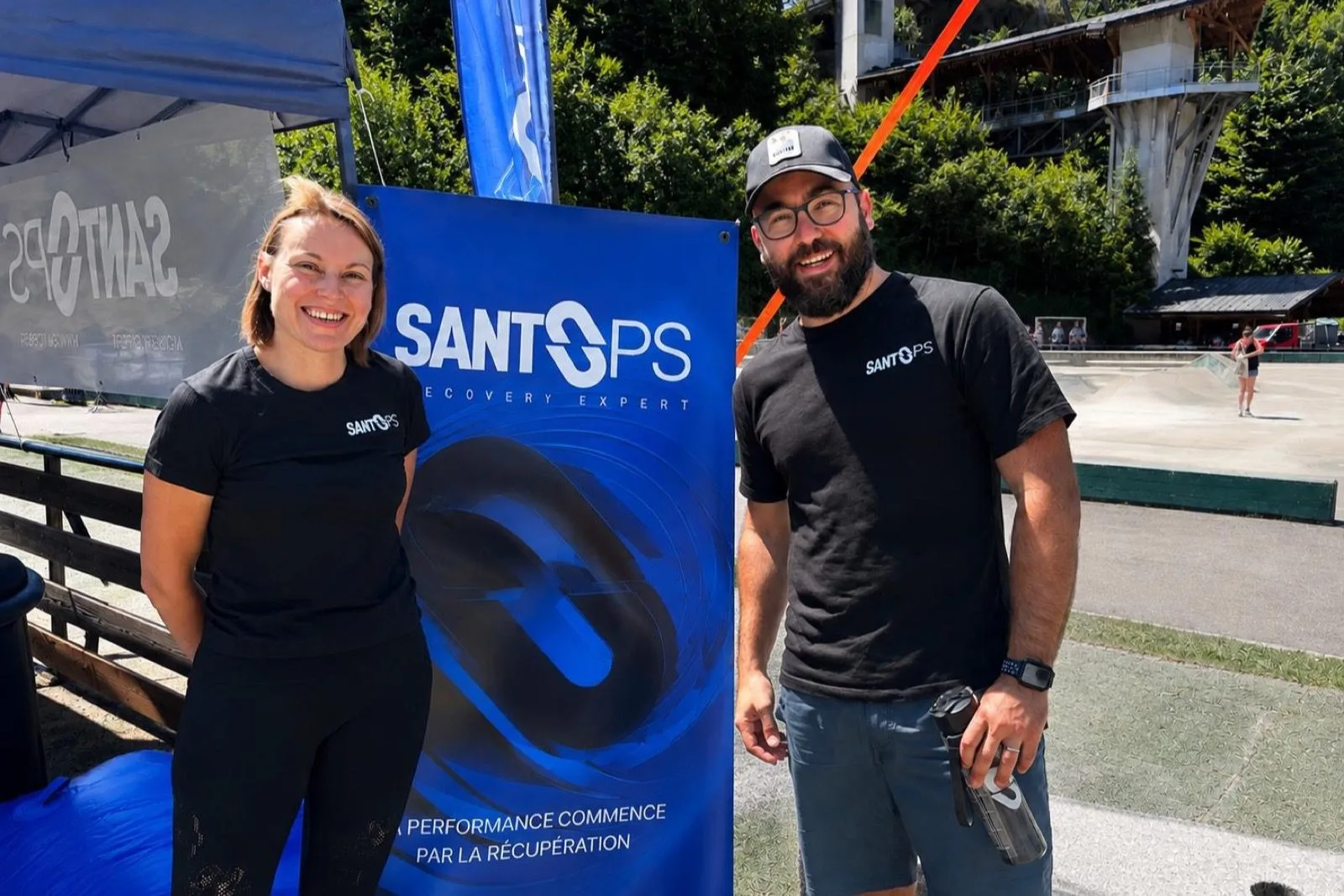 Deux membres de l'équipe SANTOPS devant le kakémono de la marque sur un événement