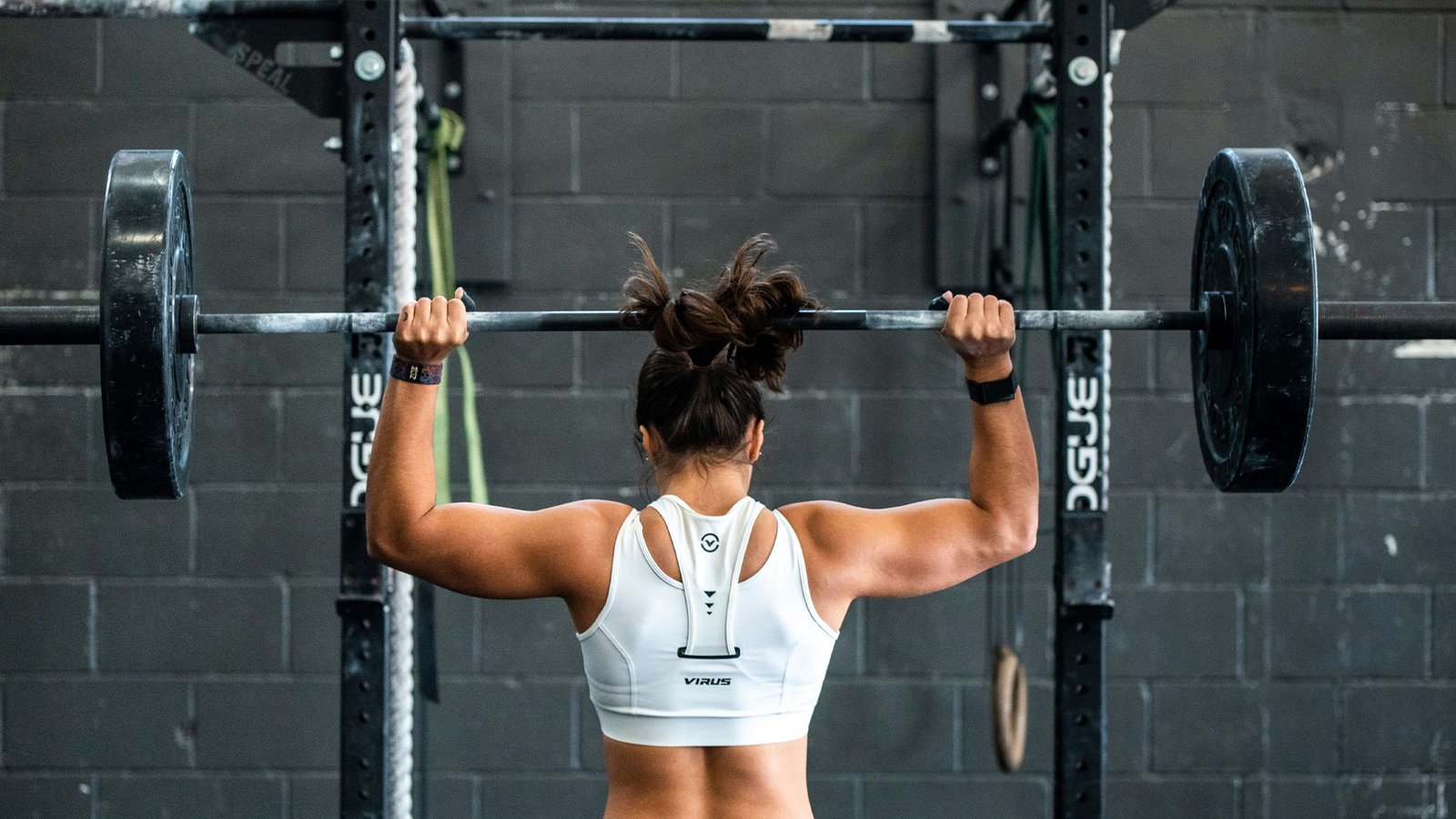 Femme athlète en position de soulevé à la barre, démontrant la technique de récupération active et prévention des compensations