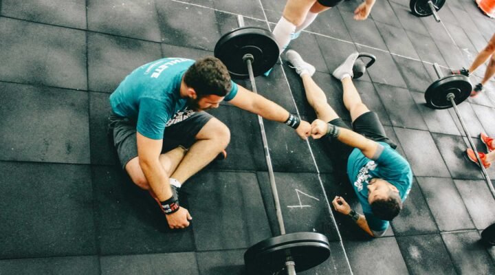 Deux athlètes en récupération active avec haltères, travail de renforcement progressif et prévention de stagnation sportive